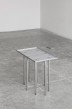 Grey small table with nine tube legs perforating the surface of the tabletop