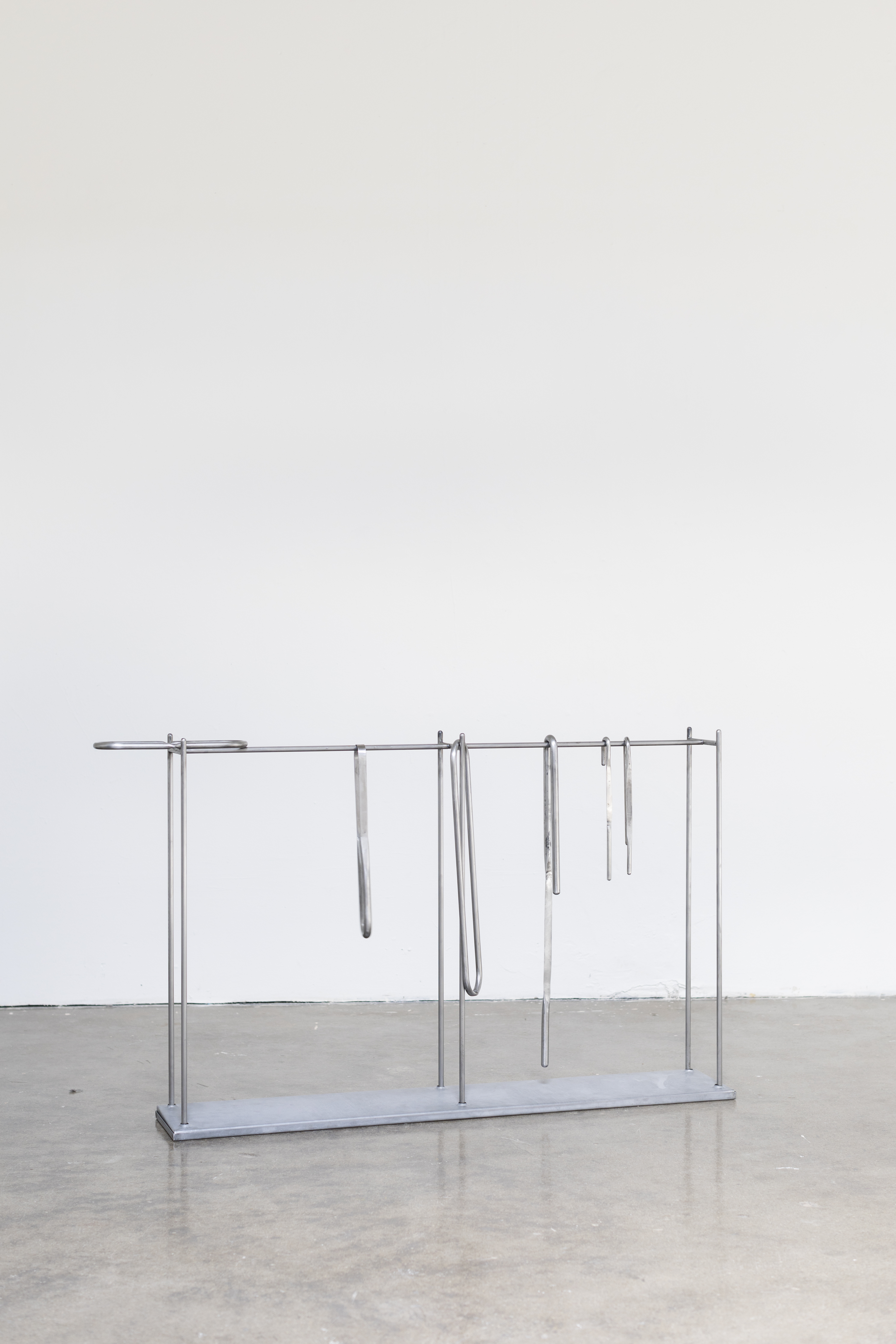 A six legged steel stand with six steel objects hooked and looped and laying on structure